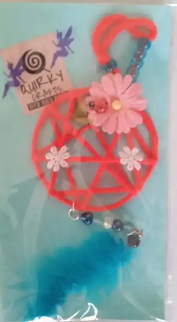 A Bright red dreamcatcher with a turquise feather handmade by Quirky Crafts